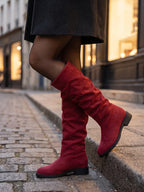 Damen Kniestiefel in Rot, getragen auf einer Kopfsteinpflastergasse