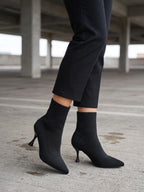 Damen Sock Boots in Schwarz, getragen an Betonsäulen