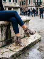 Frau auf einer Steinmauer in Damen Stiefeletten im Leopardenmuster