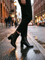Damen Stiefeletten in Schwarz, getragen auf nassem städtischem Gehweg