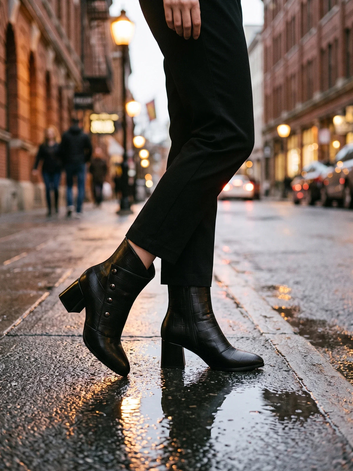 Damen Stiefeletten in Schwarz, getragen auf nassem städtischem Gehweg